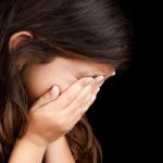 A girl is crying, covering her eyes