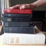 A hand upon a stack of christian bibles