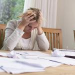 A woman works on her bills, stressed about her finances.
