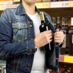 A man is stealing an alcohol bottle from a store.