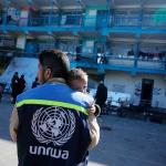 UNRWA staff member comforts a distressed child at a school shelter in Nuseirat camp, Gaza Strip. 12 March 2025