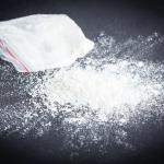 White powder spilled on a table next to a small bag containing more powder
