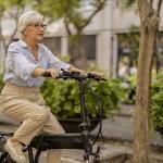 A woman is riding past urban greenery 