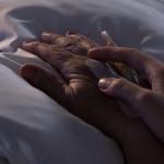 Hospice concept: Someone holding the hand of an elderly person in a bed
