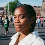 South African poet Julia-Beth Harris standing in front of Amsterdam Centraal Station in 2025