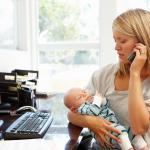 A woman works from home while looking after her baby.