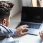 Rear view of a young man working with laptop