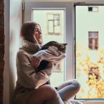 A girl and her cat sit on a windowsill 