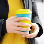 Woman holding a reusable travel mug for coffee
