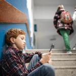Primary school boy is playing on his phone
