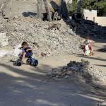 Children bike through rubble in Gaza.
