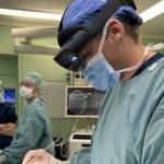 An Amsterdam UMC neurosurgeon using HoloScene mixed reality glasses to project a hologram of the brain onto a patient's head during brain surgery, January 2027