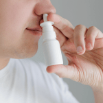 Close up of a young man using nasal spray