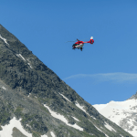An Austrian rescue helicopter flying above a snowy mountain