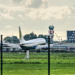 A plane touching down at Rotterdam The Hague airport with the control tower and other airport buildings in the background, 