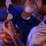Man eating chips and drinking beer in the evening.