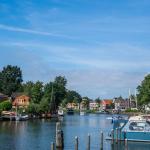Canal in the village of Blokzijl, Overijssel, lined with moored boats, traditional houses, and a white drawbridge under a clear summer sky