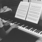 A young girl playing piano during a lesson as her instructor looks on. Jan. 2026
