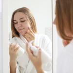 A woman with skin issues does her skincare routine.