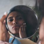 A young woman studies her reflection in the mirror.