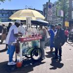 People gather at a Surinamese shaved ice stand on the Dappermarkt in Amsterdam. 25 May 2026