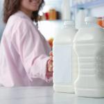 A woman reaches out for a plastic milk bottle in the fridge.