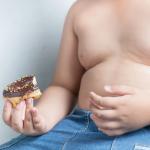 Childhood obesity: Partial view of an overweight boy holding a donut