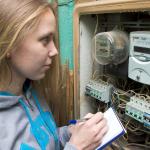 A woman notes down the number on her energy meter in order to check it.