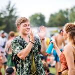 A girl sprays a guy with water at a festival.