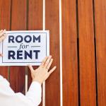 Owner hanging up sign saying room for rent