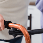 A caregiver assisting an elderly individual with a mobility walker.