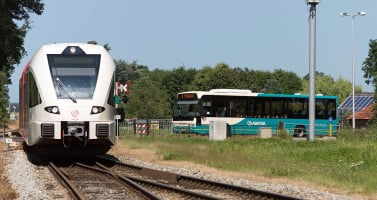 An Arriva bus waiting for an Arriva train to pass at station Lichtenvoorde-Groenlo