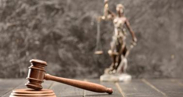 Court gavel with a statue of Lady Justice in the background
