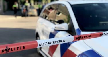 Crime scene tape and a police car, with police officers in the background