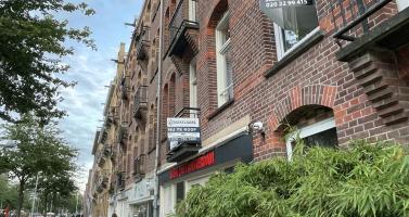 A woman walks by two homes for sale on the Javastraat in Amsterdam-Oost in July 2023.