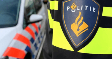 A Dutch police officer standing by a police car