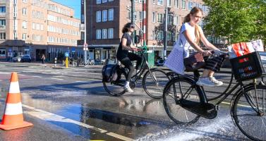 Cyclists on an Amsterdam road kept wet to cool it down during a heatwave